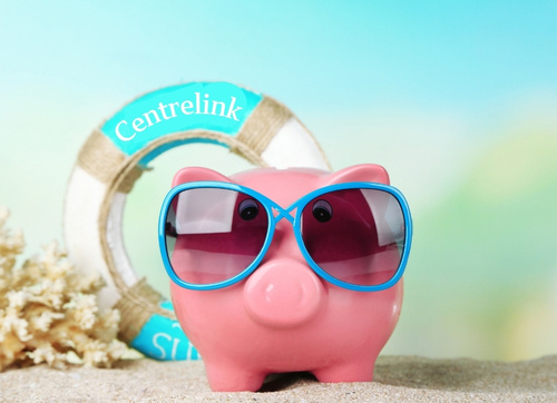 Pink piggy bank with blue sunglases standing on a beach with a lifesaving ring that says Centrelink Pink piggy bank with blue sunglases standing on a beach with a lifesaving ring that says Centrelink
